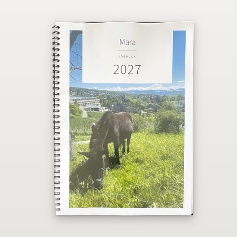 Ein gedrucktes A4-Logbuch mit Spiralbindung. Auf dem Umschlag grast ein Maultier auf einer Wiese, darüber stehen auf einem weissen Feld der Name Mara und das Jahr 2027.